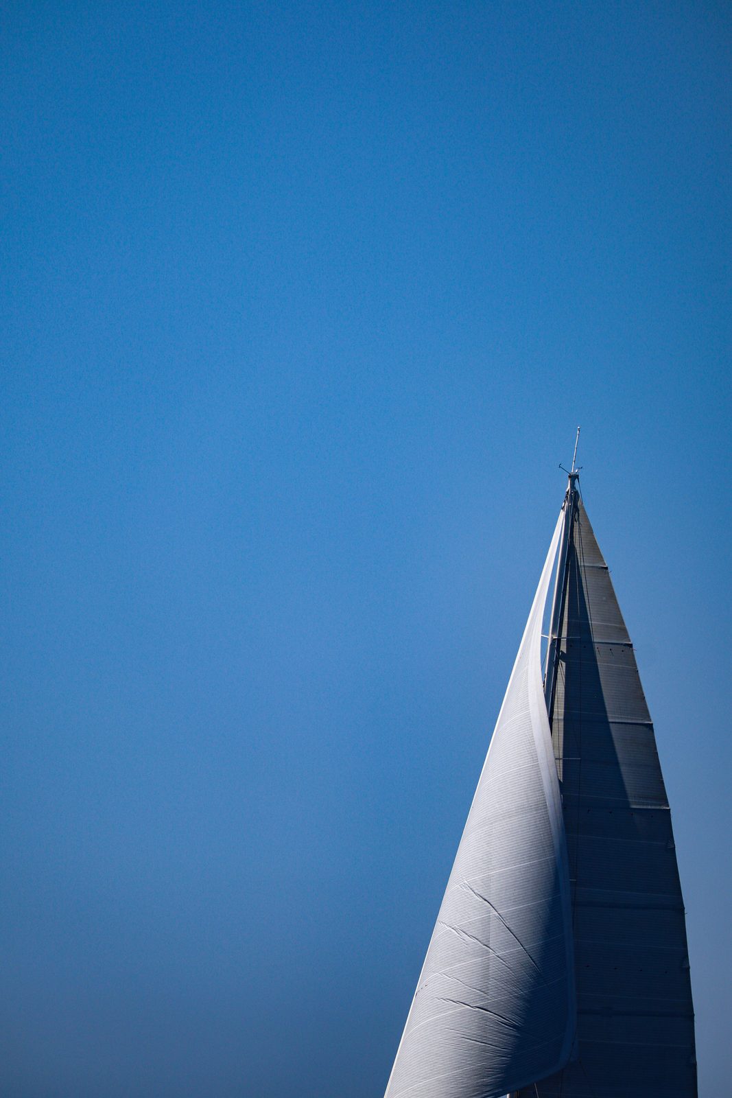 Minimalist white sail against a clear blue sky