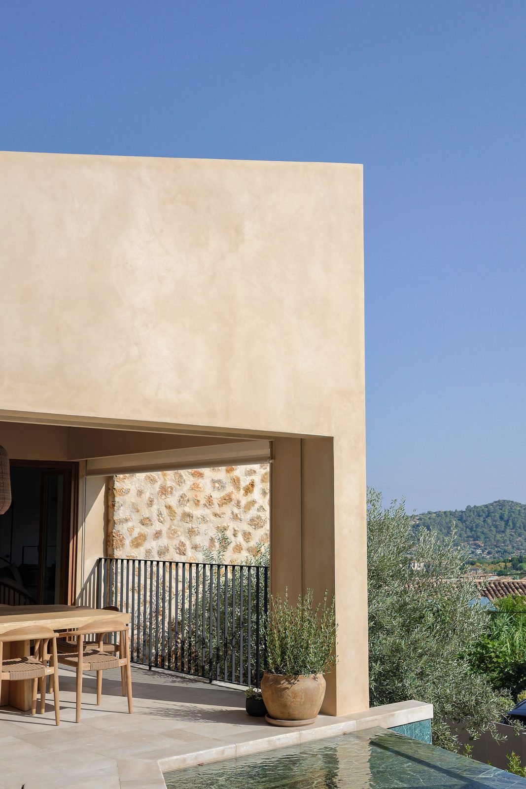 Contemporary Mallorca villa in warm render and stone with an olive tree beside a green-tiled pool